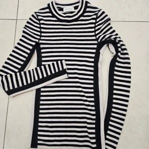 Randig svartvit tröja från Dagmar - Supersnygg långärmad tröja från Dagmar i svart och vitt med klassiskt randigt mönster. Tillverkad i 100% merinoull som är mjuk och skön mot huden. Tröjan har rund hals och en slim passform som sitter riktigt bra. Perfekt för dig som gillar stilrena vibes. Jättefin skick, nypris över 3000:-