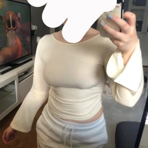 Ljusbeige ribbad långärmad topp - Säljer en krämvit ribbad topp med lång ärm och lätt utsvängda ärmslut. 