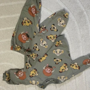 Gråa mjukisbyxor med Lejonkungen-motiv - Gråa mjukisbyxor med elastisk midja och färgglada tryck av Simba, Timon och Pumbaa från Lejonkungen. Byxorna har avslappnad passform och är perfekta för chill dagar hemma. Materialet känns mjukt och skönt mot huden.