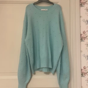 Ljusblå stickad tröja från Kappahl - Supermysig ljusblå stickad tröja från Kappahl med oversized passform och diskreta bollar som detalj. Tröjan har rund halsringning, långa ärmar och breda muddar. 