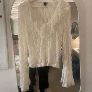 Vit spetsblus med volang från Lindex - Säljer en romantisk vit spetsblus från Lindex i storlek S. Blusen har långärmade ärmar, v-ringad hals den är helt ny aldrig använt den kom för fler frågor 💕