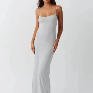 Grå långklänning med smala axelband - Supersnygg grå långklänning med smala axelband och figurnära passform. Klänningen har en enkel och stilren design som ger en clean look. Perfekt för dig som gillar minimalistisk stil och vill ha något som känns både bekvämt och trendigt.