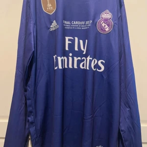 Real Madrid Ronaldo långärmad matchtröja - Säljer en blå långärmad Real Madrid fotbollströja från Adidas med Ronaldo 7 på ryggen. Tröjan har tryck från Champions League-finalen 2017 i Cardiff, klubbmärke, sponsorlogga och officiella patches på ärmarna. Tillverkad i lätt och ventilerande material.
