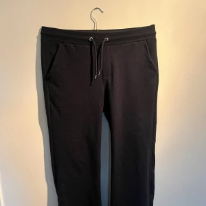 Mörkblå mjukisbyxor med snörning - Mörkblå mjukisbyxor med snörning i midjan och fickor fram samt en bakficka. Byxorna har en avslappnad passform och är gjorda i mjukt bomullsmaterial, perfekta för chill dagar. Stilren design utan mönster eller logga.