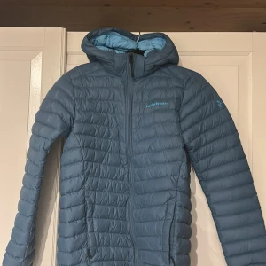 Blå dunjacka från Peak Performance 170  - Säljer en blå dunjacka från Peak Performance i storlek 170 men skulle säga att den sitter som en s/xs! Jackan  är i mycket fint skick(inga skavanker) Jackan har huva, dragkedja framtill och broderad logga på bröstet. Lätt och smidig modell med quiltad design, perfekt för lite kyligare dagar, Fodret är i ljusare blå nyans. säljer den pågrund av att den inte kommer till andvändning💕