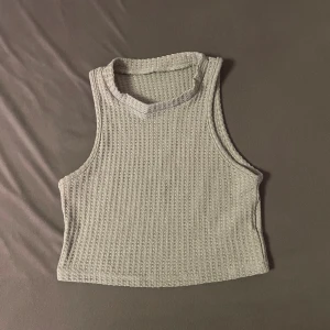 Ljusgrå ribbad långkjol med linne - Säljer en ljusgrå långkjol med ribbad struktur. Kjolen har en rak och enkel siluett som ger en clean look. Kjolen är öppen på sidan