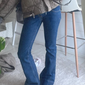 Blå bootcut jeans med mid midja - Snygga blå jeans med bootcut passform och mid midja. Jeansen har klassisk femficksdesign och är tillverkade i ett slitstarkt denimtyg. Perfekta för dig som gillar en tidlös och cool look med lite utsvängda ben.