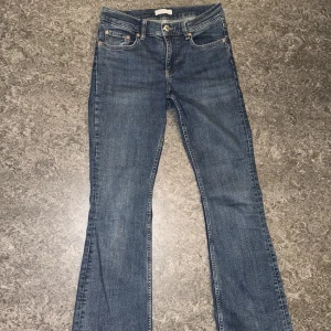 Blå bootcut jeans från Perfect Jeans - Snygga blå jeans från Perfect Jeans i klassisk bootcut-modell. Jeansen har fem fickor, orangea sömmar och knappstängning fram. Materialet är slitstarkt denim och passformen är normal med medelhög midja. Perfekt för dig som gillar en tidlös jeansstil.