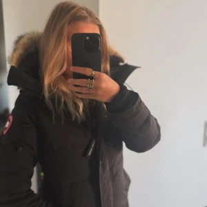 Svart lång dunjacka Canada Goose - ⸻  Canada Goose Jacka – Svart, Storlek [xs] Säljer min svarta Canada Goose-jacka, köpt 2021. Jackan är i mycket bra skick – inga hål, fläckar eller märken. Använd sparsamt och väl omhändertagen. Perfekt för vintern med den klassiska värmen och kvalitén som Canada Goose är kända för.  ✔️ Äkta Canada Goose ✔️ Köpt 2021 ✔️ Inga skador eller defekter ✔️ Färg: Svart ✔️ Pris: 8000    Original pris = 12 890