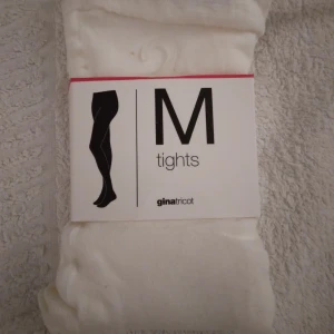 HELT NYA OANVÄNDA Offwhite / gräddvita tights / strumpbyxor från Gina Tricot,  Medium (men små) - Säljer ett par helt nya, oanvända offwhite/gräddvita tights/strumpbyxor från Gina Tricot i storlek M, men passar troligen bäst till någon med XS-S.  De är helt släta och har en mjuk, stretchig känsla tack vare blandningen av modal, polyamid och elastan. Perfekta att styla med kjol eller klänning för en clean look. Felfria.