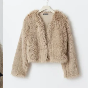 Beige pälsjacka från Gina Tricot - Säljer en fluffig och croppad beige pälsjacka från Gina Tricot. Jackan har lång ärm, öppen front och ett riktigt mjukt, lurvigt material som ger en cool och trendig vibe. Perfekt för dig som vill sticka ut med en statement piece i garderoben.