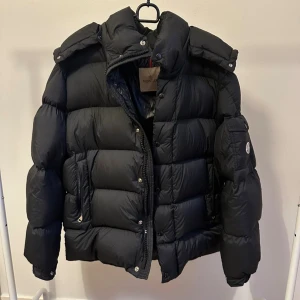 Moncler Jacka - Moncler dunjacka – svart, storlek 5  Tja! Har en snygg och exklusiv Moncler-dunjacka i svart. Köpt den förra året och endast använd en vinter – i mycket fint skick! Klassisk modell med logotyp på ärmen och äkta dunfyllning som håller dig varm hela vintern.  Pris: 5800 kr 