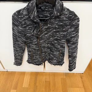 Svart och vit stickad jacka  - Säljer en svart och vit stickad jacka  med coolt randigt mönster. Jackan har grov dragkedja framtill, två fickor med dragkedja och råa kanter för en edgy vibe. Jackan köptes från magasin i Köpenhamn.
