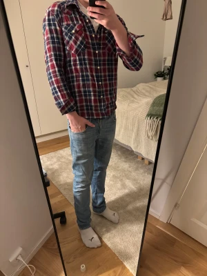 Rutig Levi's skjorta i bomull M - Säljer en klassisk rutig skjorta från Levi's i storlek M. Skjortan har en snygg mix av rött, blått och vitt, med knappar framtill och två bröstfickor. Tillverkad i mjuk bomull, perfekt för dig som gillar avslappnad stil med lite edge.