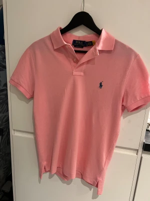Rosa pikétröja från Polo Ralph Lauren - Snygg rosa pikétröja från Ralph Lauren med noll tecken på användning. Självklart äkta.           Storlek Small.