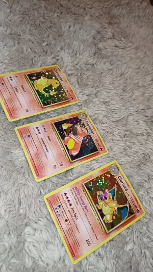Pokémon-kort: Charmander, Charmeleon & Charizard (holo) - Samlarpaket med tre holografiska Pokémon-kort: Charmander, Charmeleon och Charizard. Perfekt för dig som älskar Pokémon och vill boosta din samling med klassiska eld-Pokémon! Kortens glittrande design gör dem extra coola för både spel och display.