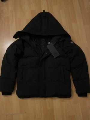 Canada Goose Macmillan - Sprillans ny Svart Canada Goose Macmillan dunjacka med Svart badge i storlek XS. Väldigt bra kvalite, samt aldrig använt endast prövat. Kommer med originella påsen & etiketter. Skriv gärna på om du har funderingar samt så är priset inte satt så hitta på förslag! 💯💬OBS: Botten dragkedjans handtag har kommit av, annars fungerar den fortfarande precis som den ska vilket är därför det låga priset (Canada Goose dragkedjan är ej märkes och kommer från YKK vilket kostar 200kr~ att fixa i skrädderi.)