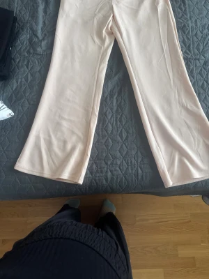 Beige bootcut byxor från SHEIN - Snygga ljusbeige bootcut-byxor från SHEIN i storlek M. Byxorna har en mjuk och slät yta, med utsvängda ben och en enkel design utan synliga detaljer. Perfekta för dig som gillar stilrena och bekväma byxor med lite extra vidd nertill.