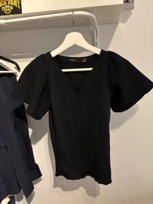 Svart blus med puffärm Vero Moda - Svart blus från Vero Moda i storlek S. Modellen har breda puffärmar och en snygg v-ringad hals. Perfekt för dig som gillar stilrena och trendiga plagg.