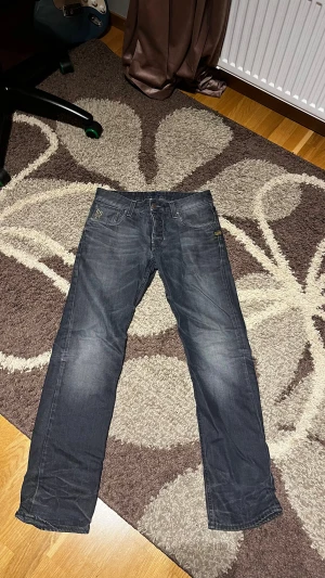 Mörkgrå jeans från G-Star RAW - Tja! Säljer ett par grymt sköna Jeans ifrån Gstar, sjukt coola med dragkedjan där bak. One of a kind helt enkelt!