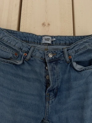 Blå raka jeans från 157 - Klassiska blå jeans från 157 med raka ben och normal passform. Jeansen har fem fickor, knappgylf och bälteshällor. Tillverkade i slitstarkt denimtyg som ger en tidlös look. Perfekta för dig som gillar enkel och clean stil.