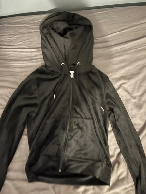 Svart hoodie och svarta byxor  i sammet från Gina Tricot - Svart hoodie och svarta byxor  från Gina Tricot i mjuk sammet med dragkedja och stor huva. Tröjan har snörning vid halsen, långa ärmar och en praktisk ficka framtill. Perfekt för chill dagar och har en snygg ringdetalj på dragkedjan.fickor på baksidan, 