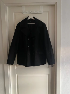 Svart skepparkavaj  - Stilren, klassisk och knappt använd. Modellen är dubbelknäppt med snygga slag och två fickor fram. Perfekt för både vardag och mer uppklädda tillfällen. Väldigt bra passform och kvalitet. Öppen för bud!