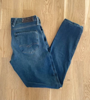 Blå Replay Anbass W30 - Jag säljer dom här riktigt feta Replay Anbass jeansen som är i storlek W30. De är upplagda så utgå ifrån måtten. De är i fint skick utan skador. Tveka inte att höra av er!                                        Mått: Längd=92cm. Midja=37cm