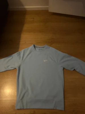 Nike NOCTA sweatshirt  - Nike NOCTA crewneck i ljusblått med vit swoosh på bröstet och NOCTA-logga på ärmen. Tröjan har rund hals, långa ärmar och är gjord i mjuk bomull/polyester-blandning. Snygga detaljer med NOCTA-tryck i nacken och stilren design.