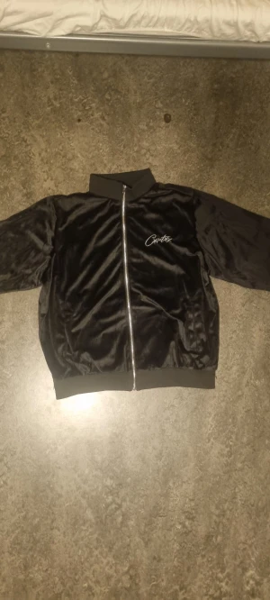 CORTEIZ Svart Zip Tröja - Svart Oversized Corteiz Velour Zip tröja i mjuk, glansig material med broderad logga fram och stort broderi på ryggen. Passar mig ganska oversized som är (175cm-70kg) därför jag säljer den, skulle passa någon större elr ngn som gillar oversized.