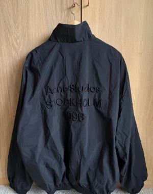 Acne Studios 1996 Stockholm jacka  - Acne Studios Embroidered Logo Zip Jacket, storlek M och i nyskick.  Nypris 7 500 kr. Kommer från ett djur- och rökfritt hem. Skickas snabbt och tryggt. Broderad logga, snygg passform och högkvalitativt material.  Länk till produkten: https://www.acnestudios.com/se/en/logo-jacket-black/B90800-900044.html?utm_source=google&utm_medium=cpc&dema_id=2052832534&utm_content=73733672583&utm_term=&gadid=359621037111&gad_source=1&gad_campaignid=2052832534&gbraid=0AAAAADAkw6HxJYfNMIBrve5FZ8nXXpI9P 