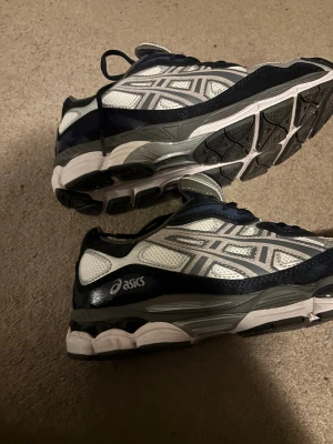 Asics GEL-NYC sneakers steel grey - Säljer ett par Asics GEL-NYC sneakers i färgen cream/steel grey. Skorna har en chunky sula, mesh-paneler och detaljer i mörkblått, grått och vitt. Klassisk Asics-logga på sidan och snörning framtill. Perfekt för dig som gillar retrovibbar och sportig stil. Bara testade pris kan diskuteras 