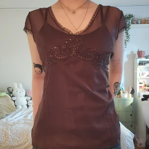 Brun blus med spets och paljetter - Brun blus och linne med transparent mesh och paljetter upptill.