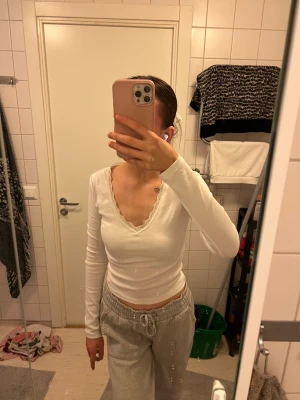 Vit topp från Gina Tricot - Säljer en vit ribbad långärmad topp från Gina Tricot i storlek S. Toppen har v-ringning med spetskant och är croppad i modellen. Perfekt för dig som gillar enkla men snygga detaljer. Använd 1-2 gånger! Nypris: 279-299kr.