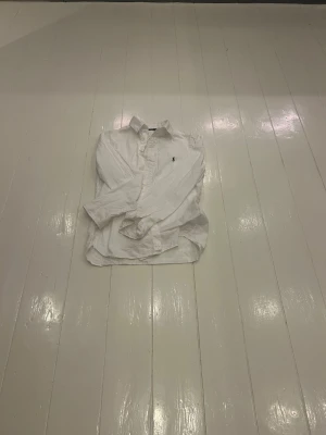 Vit skjorta Polo Ralph Lauren slim fit - Vit långärmad skjorta från Polo Ralph Lauren i slim fit-modell. Klassisk krage, knäppning framtill och ikoniska broderade loggan på bröstet. Skjortan är tillverkad i bomull och har en stilren och tidlös look.