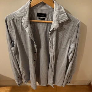Rutig skjorta från Massimo Dutti - Snygg rutig skjorta från Massimo Dutti. Skjortan har långa ärmar och svart knappar. Perfekt för en stilren look eller under en snygg tröja. Skjortan har används 2 gånger men är ej struken därav något skrynklig.