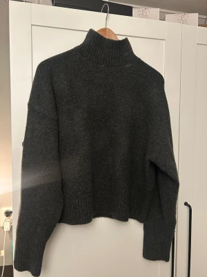 Mörkgrå polotröja från Zara - Säljer en mörkgrå polotröja från Zara i storlek S. Tröjan är stickad med ribbad hög krage och muddar vid ärmslut och nederkant. 