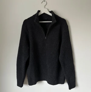 Mörkgrå stickad half zip-tröja M - Mörkgrå stickad tröja från Uniqlo i storlek M. Modellen har en ribbad krage och half zip-dragkedja framtill. Materialet är mjukt och värmande, perfekt för kyliga dagar. Långärmad och med klassisk, enkel design som funkar till många olika stilar. 5H12