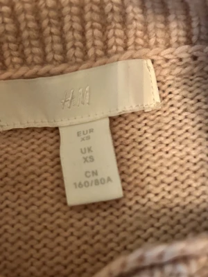 Beige polotröja från H&M XS - Snygg beige polotröja från H&M i storlek XS. Tröjan är stickad med ribbade detaljer vid hals, ärmslut och nederkant. Den har lång ärm och en hög krage som ger en chill vibe. Perfekt för lager-på-lager och passar till jeans eller kjol.
