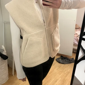 Beige teddyväst från Carin Wester XS - Mysig beige teddyväst från Carin Wester. Västen har två stora fickor framtill, dragkedja och är tillverkad i mjuk polyester med bomullsfoder. Perfekt att slänga över en långärmad tröja för extra värme och stil. Köpte förra veckan och är använd 1 gång