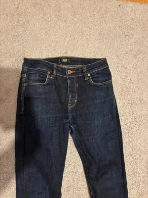 Mörkblå jeans från Neuw W30 L32 - Snygga mörkblå jeans från Neuw med klassisk femficksdesign och kontrastsömmar. Modellen har rak passform och normal midja, med läderpatch bak och coola detaljer på bakfickorna. Perfekt för dig som gillar stilrena och tidlösa jeans.