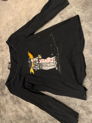 Svart långärmad tröja Sonia Rykiel - Cool svart långärmad tröja från Sonia Rykiel med unik grafisk print framtill i vitt, rött och gult samt små pärldetaljer. Tröjan har en avslappnad passform och är tillverkad i mjuk bomull, perfekt för dig som gillar statement-plagg.