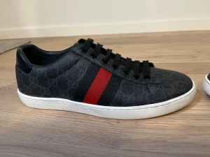 Gucci Ace svarta  - Svarta Gucci Ace i väldigt bra skick. Storleken är 43 men passar även 42. Orginalbox och dustbag följer med. Priset är inte helt hugget i sten så hör av dig vid intresse.