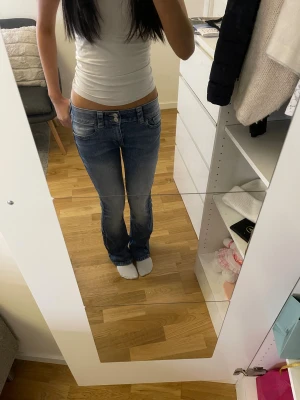 Blå bootcut jeans med låg midja - Snygga blå jeans med bootcut och låg midja, klassisk femficksdesign och dubbla knappar fram. I stl 164, justerbar midja. Nyskick. 💕Skriv om du har frågor, kolla min profil för annat fint