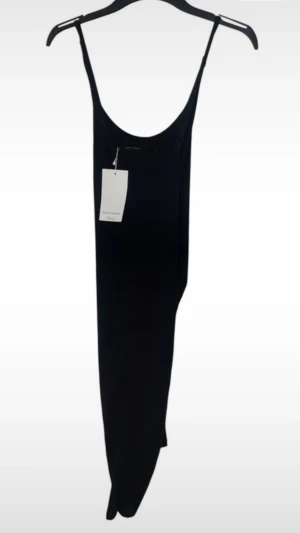 Svart asymmetrisk långklänning Zara - Säljer en svart långklänning från Zara Collection Evening. Klänningen har smala axelband, en asymmetrisk draperad detalj i nederkanten och är tillverkad i ett mjukt, tunt material som faller snyggt. Perfekt för dig som gillar minimalistisk och stilren design.