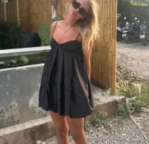 Svart babydoll klänning med tunna axelband - Supersöt svart babydoll klänning med tunna axelband och voluminös kjol. Klänningen har en luftig passform och snygga veck framtill som ger extra rörelse. Perfekt för dig som gillar en trendig och lekfull look. Materialet är glansigt och känns mjukt mot huden. Kan gå ner i pris vid snabb affär! 