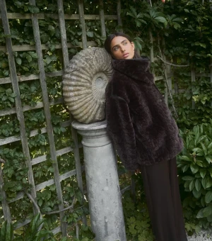 Mörkbrun pälsjacka med hög krage - Säljer en fluffig mörkbrun pälsjacka från Gina  med hög krage och breda ärmar. Jackan har snygga svarta kantdetaljer och stängs med knappar framtill. Perfekt för dig som vill ha en statement piece i garderoben och gillar att sticka ut med din stil.