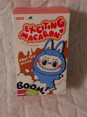 Typ Labubu The Monsters med box Exciting Macaron BOOM! Vinyl Face typ Labubu - Pop Mart typ Labobo med box Exciting Macaron The Monsters Vinyl Face samlarfigur, levereras i en box originalförpackning och en innerpåse innehållandeen typ Labobo. Perfekt för samlare av designerleksaker och Pop Mart-figurer.