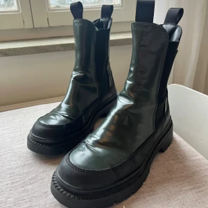Chunky svart/gröna boots från Gant - Säljer ett par chunky svart/gröna chelsea boots från Gant i storlek 38. Skorna har grov sula, rund tå och elastiska partier på sidorna.