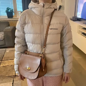 Ljusbeige dunjacka Peak Performance - Snygg ljusbeige dunjacka från Peak Performance med huva och dragkedja. Jackan är quiltad och har en clean look med diskret logga på bröstet. Perfekt för kalla dagar och har en normal passform som funkar till det mesta. Strl M men passar även xs/s så sitter den på xs/s. Använd gärna köp nu💕